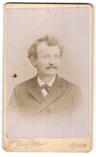 Fotografie P. Grandjean, Paris, Portrait stattlicher Mann mit lockigem Haar und Schleife im Anzug