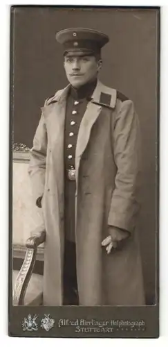 Fotografie Alfred Hirrlinger, Stuttgart, Portrait Soldat in Uniformmantel mit Schirmmütze