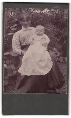 Fotografie unbekannter Fotograf und Ort, Portrait Frau mit Säugling im Garten