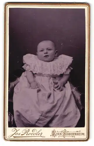 Fotografie Jos. Roeder, Kirn-Sobernheim, Portrait Säugling in Kleidchen