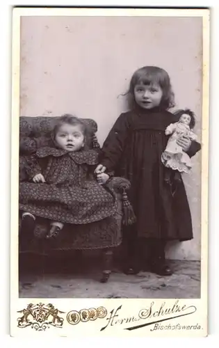 Fotografie Herm. Schulze, Bischofswerda, Portrait Mädchen mit Puppe und kleine Schwester