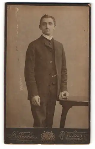 Fotografie J. Fuchs, Dresden, freundlicher junger Mann im Anzug am Stuhl stehend