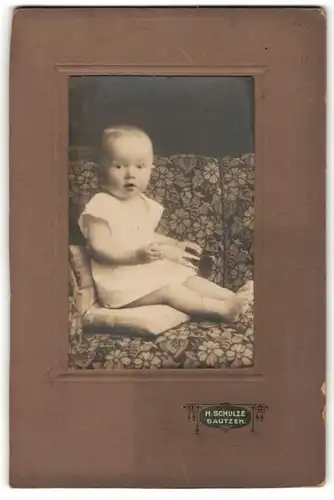 Fotografie H. Schulze, Bautzen, niedliches blondes Kleinkind mit nackten Füssen und Spielzeug