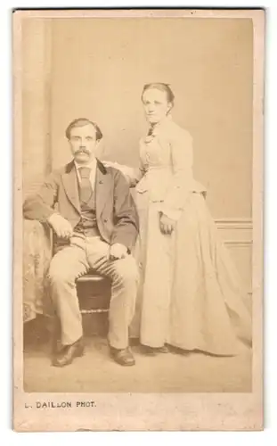 Fotografie L. Daillon, Paris, hübsche junge Frau im weissen Kleid & junger Mann mit Schnauzer im Anzug