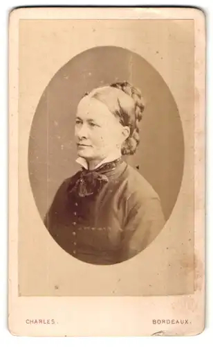 Fotografie Charles, Bordeaux, Portrait hübsche ältere Dame mit Flechtfrisur und Schleife am Kragen