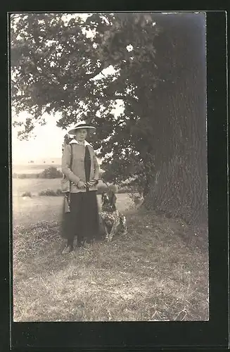 Foto-AK Jägerin mit Gewehr und Hund unter einem Baum