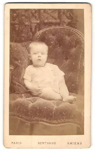 Fotografie Berthaud, Paris, Kleinkind mit Halskette im Polstersessel sitzend