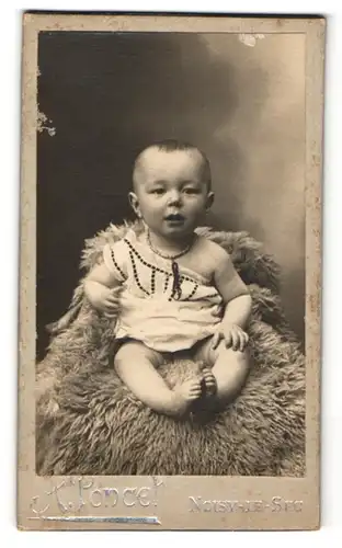 Fotografie A. Poncet, Noisy-le-Sec, Baby auf einem grossen Fell sitzend