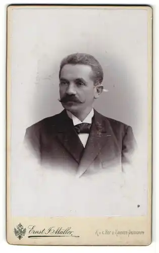 Fotografie Ernst J. Müller, Reichenberg, Portrait charmanter Herr mit Schnurrbart im schwarzen Anzug