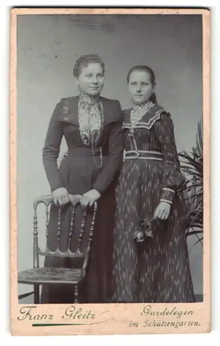 Fotografie Franz Gleitz, Gardelegen, zwei schöne junge Frauen im prachtvollen Kleidern und Rose in der Hand