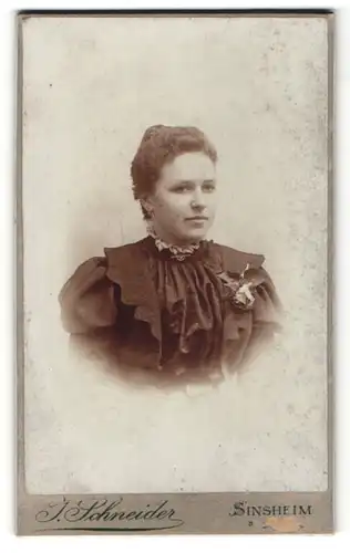 Fotografie J. Schneider, Sinsheim, Portrait hübsches Fräulein mit Dutt in prachtvoller Rüschenbluse und Ansteckbluse
