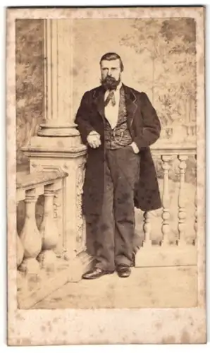 Fotografie Duboso, Abbeville, Mann im schwarzem langen Jacket auf einer veranda posierend