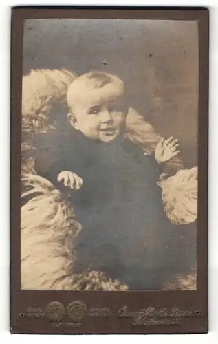 Fotografie Oscar Rothe, Dresden, Portrait niedliches blondes Kleinkind auf einem Fell