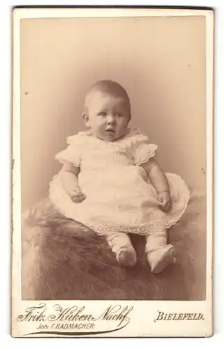 Fotografie Fritz Küken Nachf., Bielefeld, Portrait niedliches Baby im weissen Festkleid