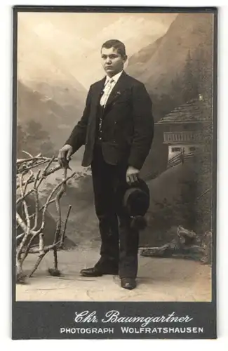 Fotografie Chr. Baumgartner, Wolfratshausen, Portrait junger Mann im Anzug mit Hut