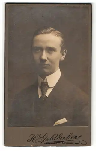 Fotografie H. Goldbecker, Gütersloh, Portrait junger charmanter Mann mit zurückgekämmtem Haar im Anzug