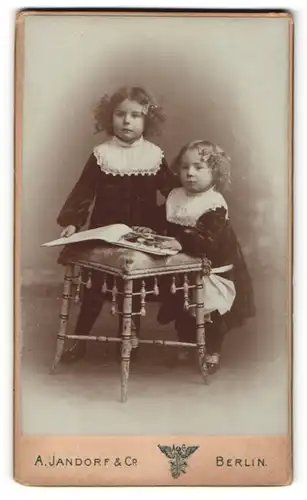Fotografie A. Jandorf & Co, Berlin, zwei bezaubernde kleine Mädchen mit Haarschleifen und grossem Buch