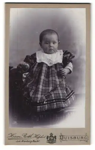 Fotografie Herm. Roth, Duisburg, Portrait Säugling in kariertem Kleidchen