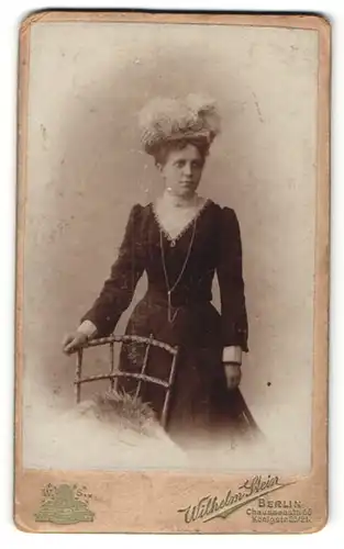 Fotografie Wilhelm Stein, Berlin, Portrait schöne Dame mit interessantem Hut im besticktem Kleid