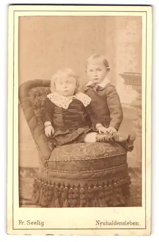Fotografie Fr. Seelig, Neuhaldensleben, Zwei kleine Kinder an Polsterstuhl
