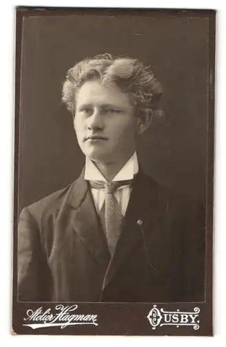 Fotografie Atelier Hagman, Ousby, Portrait junger blonder Mann mit Mittelscheitel und Krawatte im Anzug