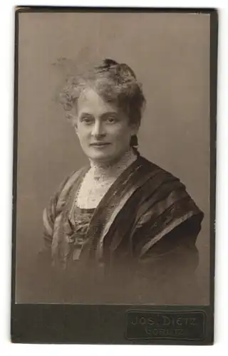 Fotografie Jos. Dietz, Görlitz, Portrait charmant lächelnde Dame mit Dutt in aufwendig bestickter Bluse