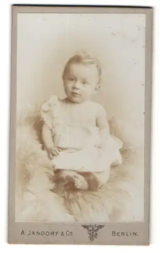 Fotografie A. Jandorf & Co, Berlin, lächelndes kleines Mädchen mit blondem Haar im weissen Kleidchen