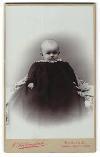 Fotografie F. Schloenbach, Berlin, Portrait Babykopf guckt aus dem grossen Taufkleid