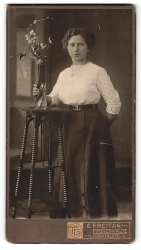 Fotografie E. Freitag, Finsterwalde, Junge Frau stehend an Beistelltisch mit Vase und Blumen