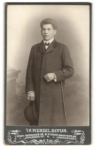 Fotografie Th. Wenzel, Berlin, Junger Mann mit Mantel, Hut und Gehstock