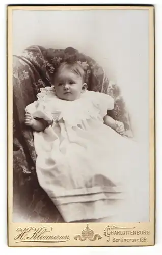 Fotografie H. Kleemann, Charlottenburg, Baby im Kleidchen im Sessel liegend