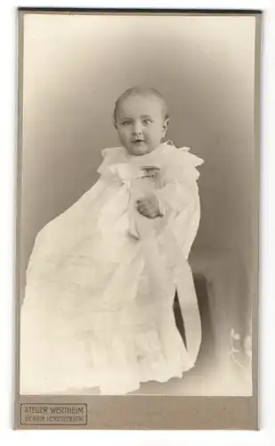 Fotografie Atelier Wertheim, Berlin, lachendes kleines Mädchen im weissen Taufkleid mit Schleife