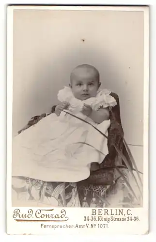 Fotografie Rud. Conrad, Berlin, zuckersüsses Baby im weissen Rüschenkleidchen
