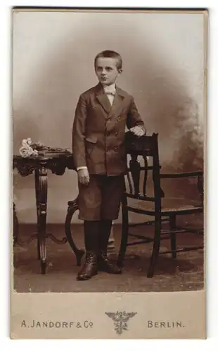 Fotografie A. Jandorf & Co, Berlin, frecher Bube mit kurzem Haar und Schürstiefeln im Anzug