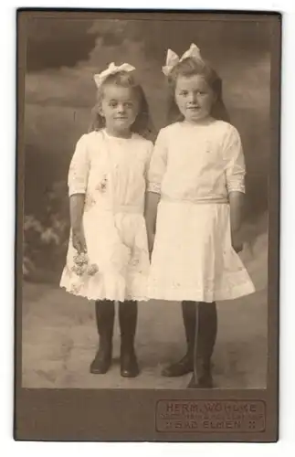 Fotografie Herm. Wöhlke, Bad Elmen, Portrait zwei kleine Mädchen in Kleidern mit Haarschleife