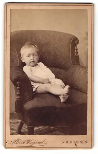 Fotografie Albert Wigand, Nordhausen, lachender blonder Bube im weissen Hemdchen im Sessel sitzend