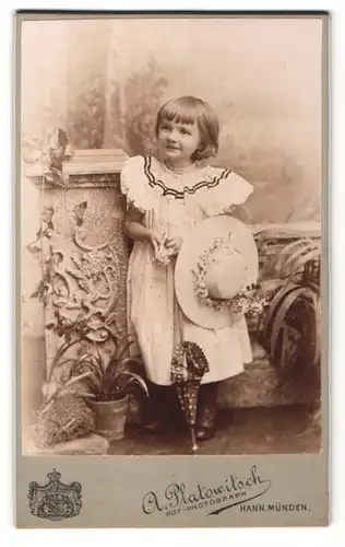 Fotografie A. Platowitsch, Hann. Münden, lächelndes blondes Mädchen mit Blumenhut und Schirm im Kleidchen