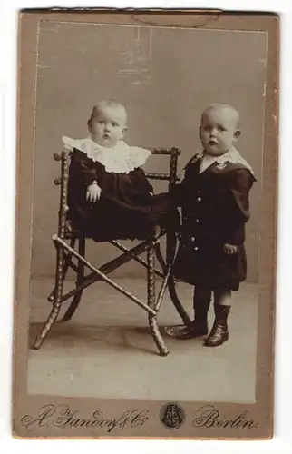 Fotografie A. Jandorf & Co., Berlin, zwei bezaubernd süsse Kleinkinder in dunklen Kleidern mit weissen Spitzenkragen