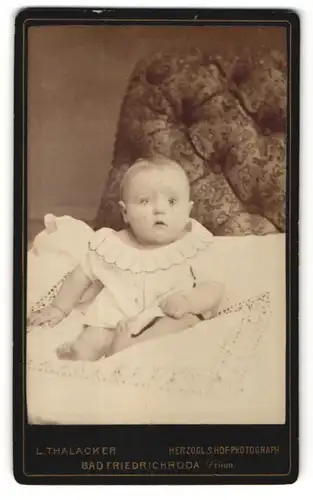 Fotografie L. Thalacker, Bad Friedrichroda / Thür., zuckersüsses Baby mit grossen Augen im weissen Kleidchen