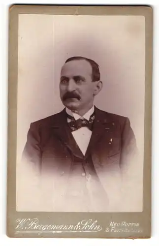 Fotografie W. Bergemann & Sohn, Neuruppin, Portrait dunkelhaariger Mann mit Halbglatze und Schnauzer im Anzug