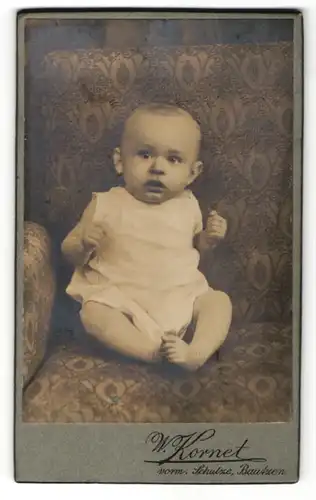 Fotografie W. Kornet, Bautzen, zuckersüsses Baby im weissen Hemdchen im Sessel sitzend