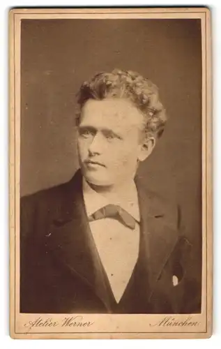 Fotografie Ateleir Werner, München, Portrait Mann mit Locken im Anzug mit Fliege