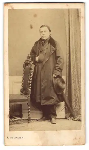 Fotografie F. Neumayer, München, Portrait Mann im Mantel mit Hut und Schirm