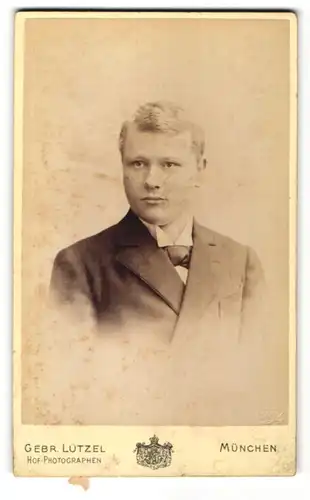 Fotografie Gebr. Lützel, München, Portrait junger Mann im Anzug mit Fliege