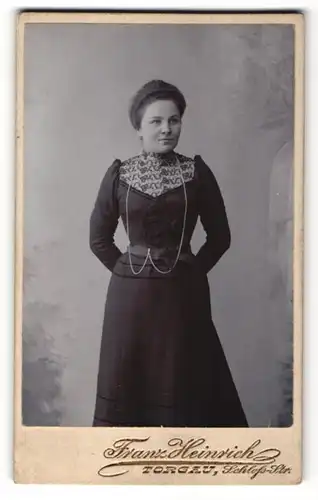 Fotografie Franz Heinrich, Torgau, Portrait lächelnde junge Dame in besteickter Bluse und Halskette
