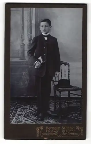 Fotografie Hermann Schöne, Dresden, Portrait Junge mit Fliege und Buch im Anzug
