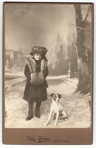 Fotografie Hans Koren, Köflach, niedliches Mädchen mit Pelzmuff und Hut nebst Hund auf verschneiter Strasse
