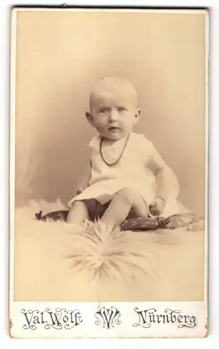 Fotografie Val. Wolf, Nürnberg, Portrait Kind sitzend auf einem Kissen