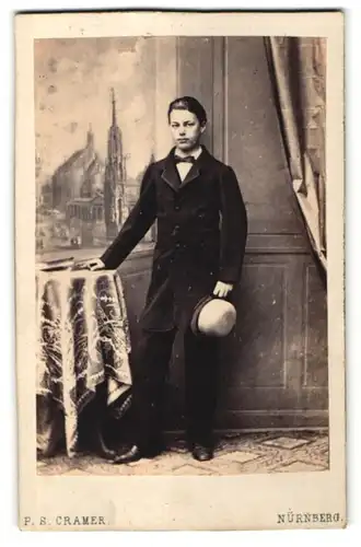 Fotografie P.S. Cramer, Nürnberg, Portrait Junge mit Hut posiert an einem Tisch