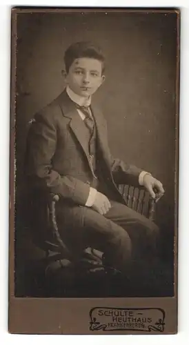 Fotografie Schulte-Heuthaus, Frankenberg i. / S., Portrait Junge mit Krawatte im karierten Anzug auf einem Stuhl